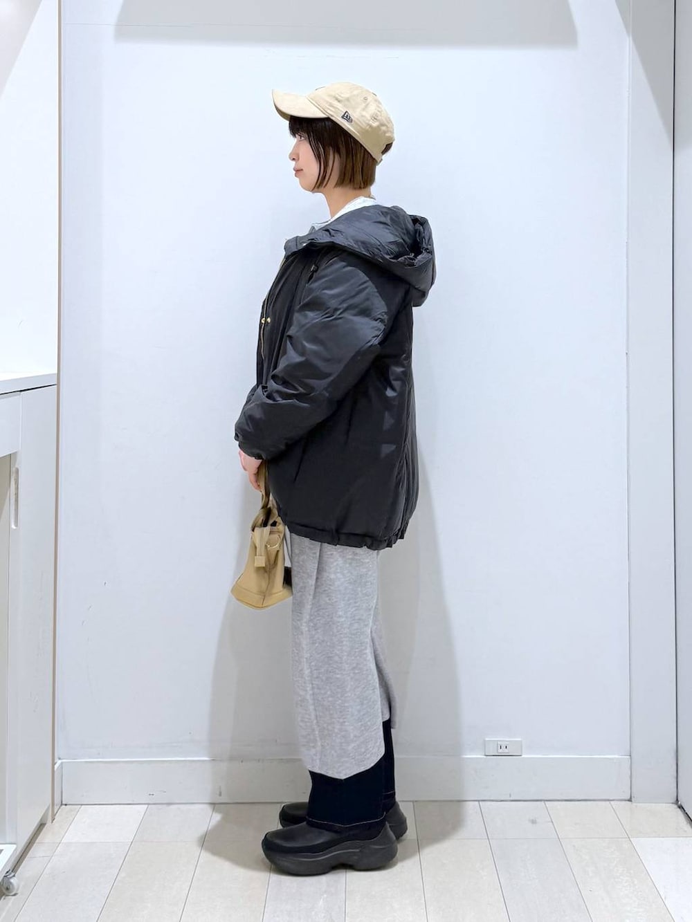 ブラウン系のトートバッグ、ブルー系のダウンジャケット/コート、ブルー系のデニムパンツを着用したレディースの冬コーディネートの2枚目の写真