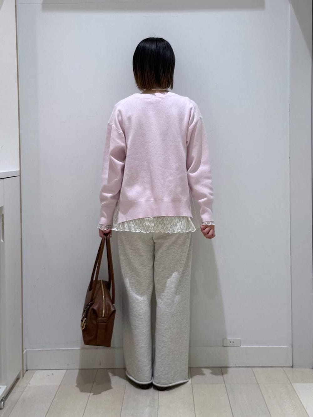 ブラウン系のボストンバッグ、ピンク系のニット/セーター、ホワイト系のスウェットパンツを着用したレディースの春コーディネートの3枚目の写真