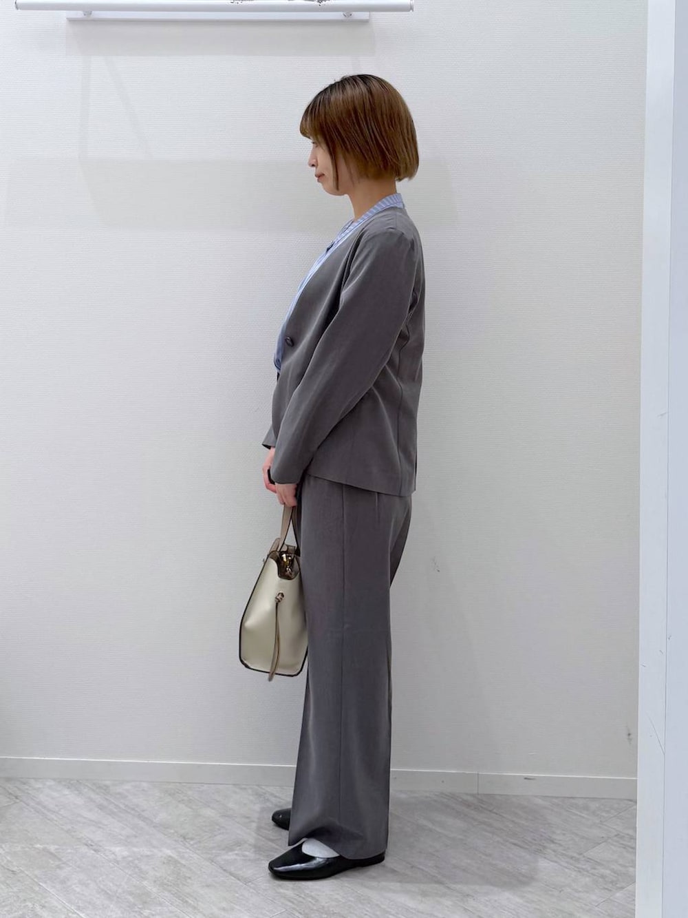ブラック系のパンプス、ベージュ系のショルダーバッグ、ブルー系のシャツ/ブラウスを着用したレディースの春コーディネートの2枚目の写真