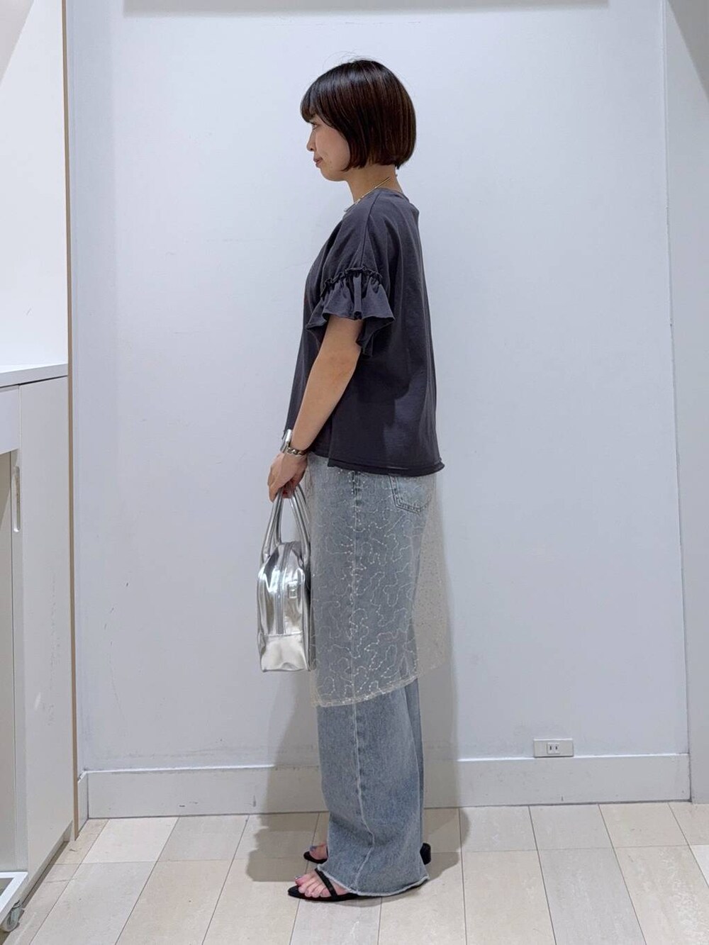 ブルー系のデニムパンツ、グレー系のボストンバッグ、ブラック系のTシャツ/カットソーを着用したレディースの夏コーディネートの2枚目の写真