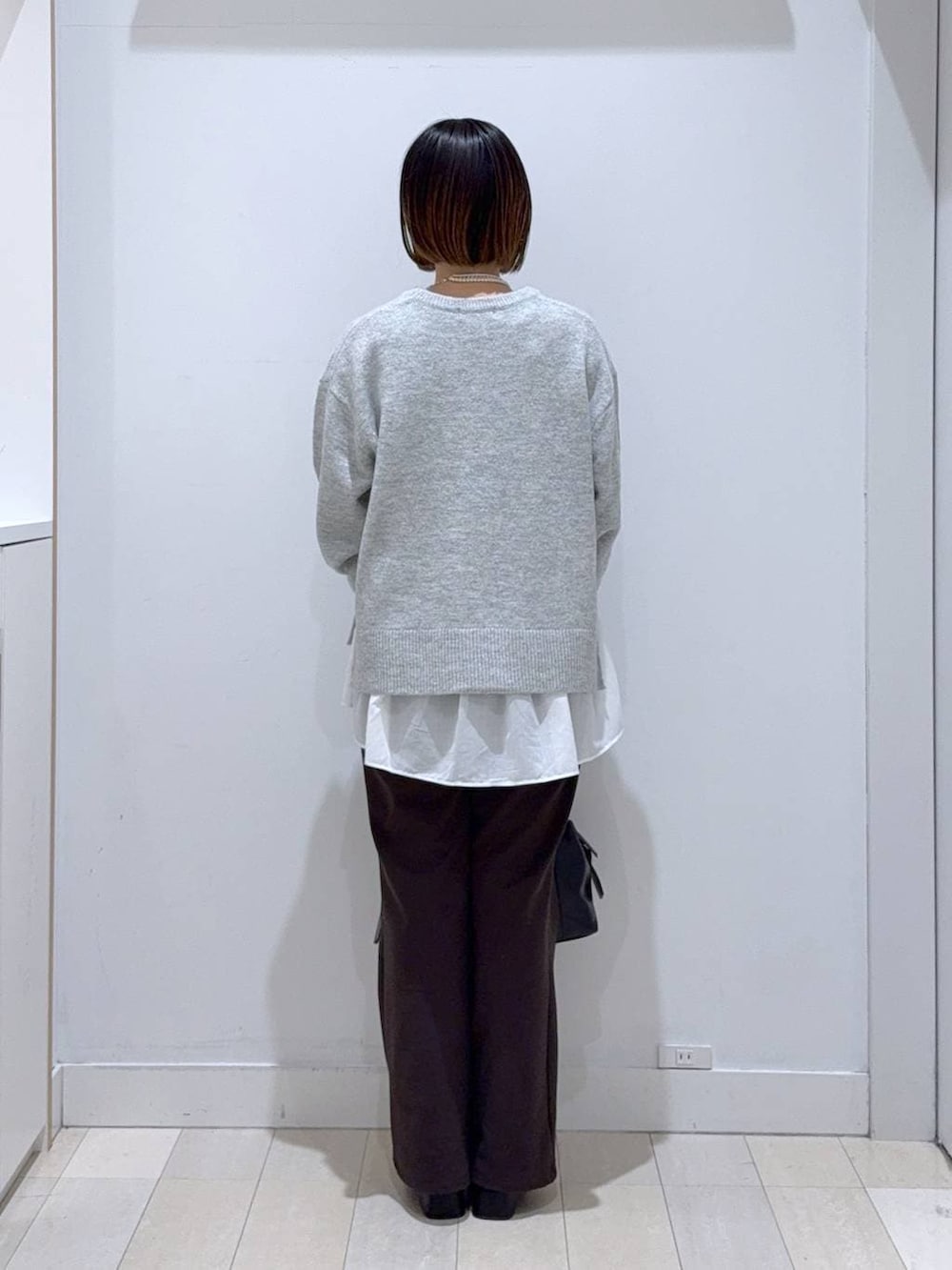 ブラック系のボストンバッグ、シルバー系のニット/セーター、ホワイト系のTシャツ/カットソーを着用したレディースの冬コーディネートの3枚目の写真