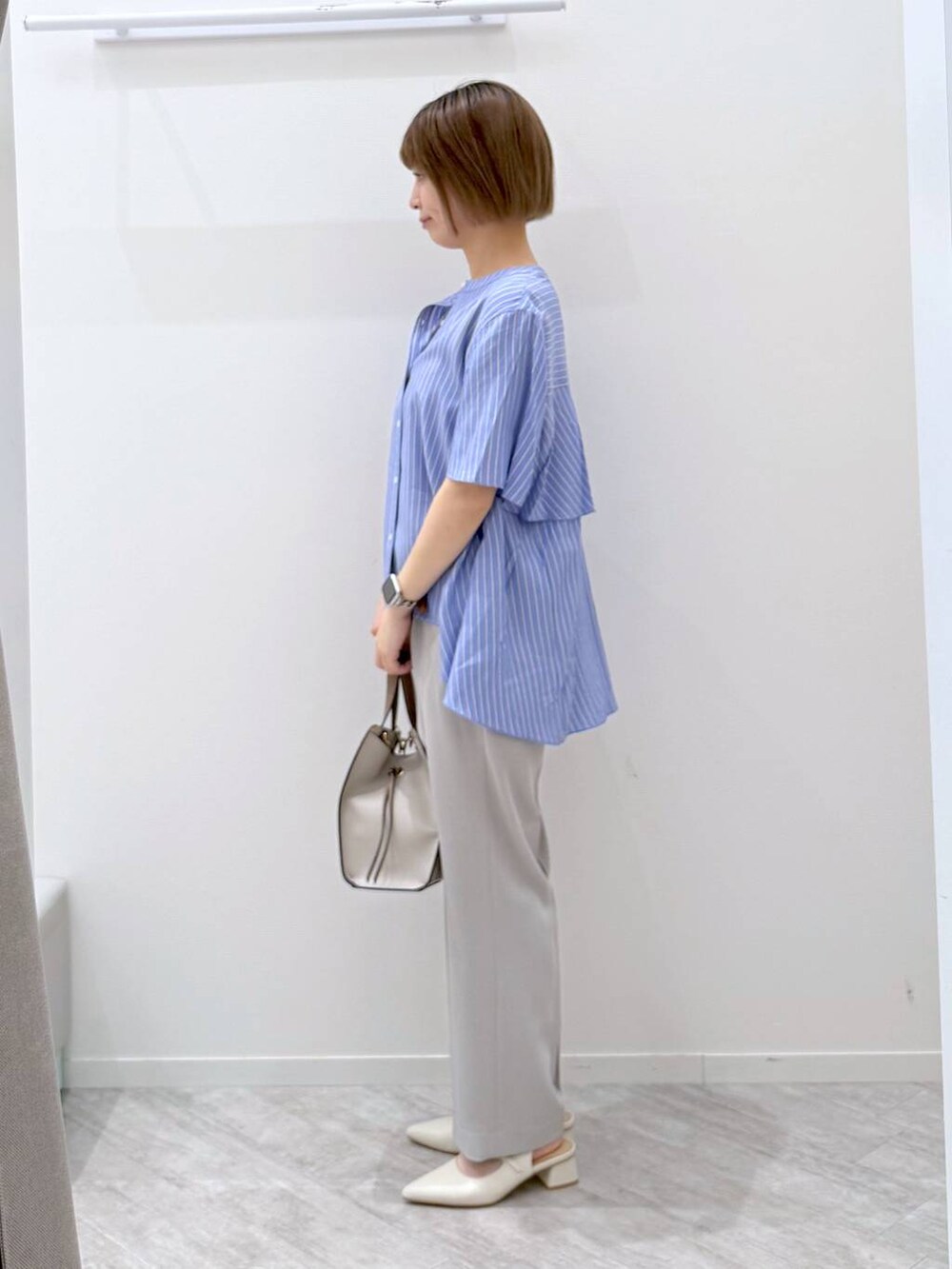 ホワイト系のショルダーバッグ、グレー系のスラックス、その他のシャツ/ブラウスを着用したレディースの春コーディネートの2枚目の写真