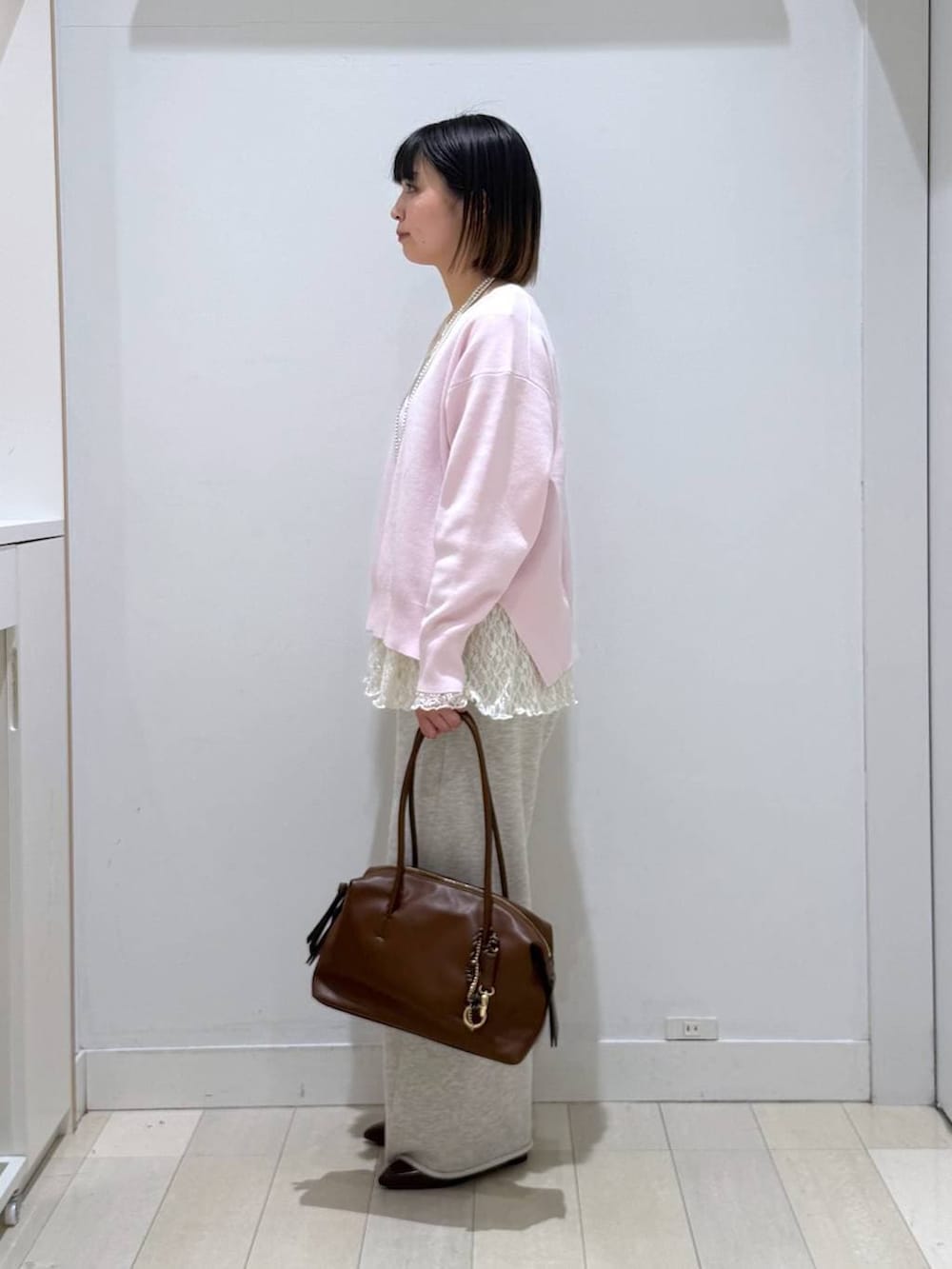 ブラウン系のボストンバッグ、ピンク系のニット/セーター、ホワイト系のスウェットパンツを着用したレディースの春コーディネートの2枚目の写真