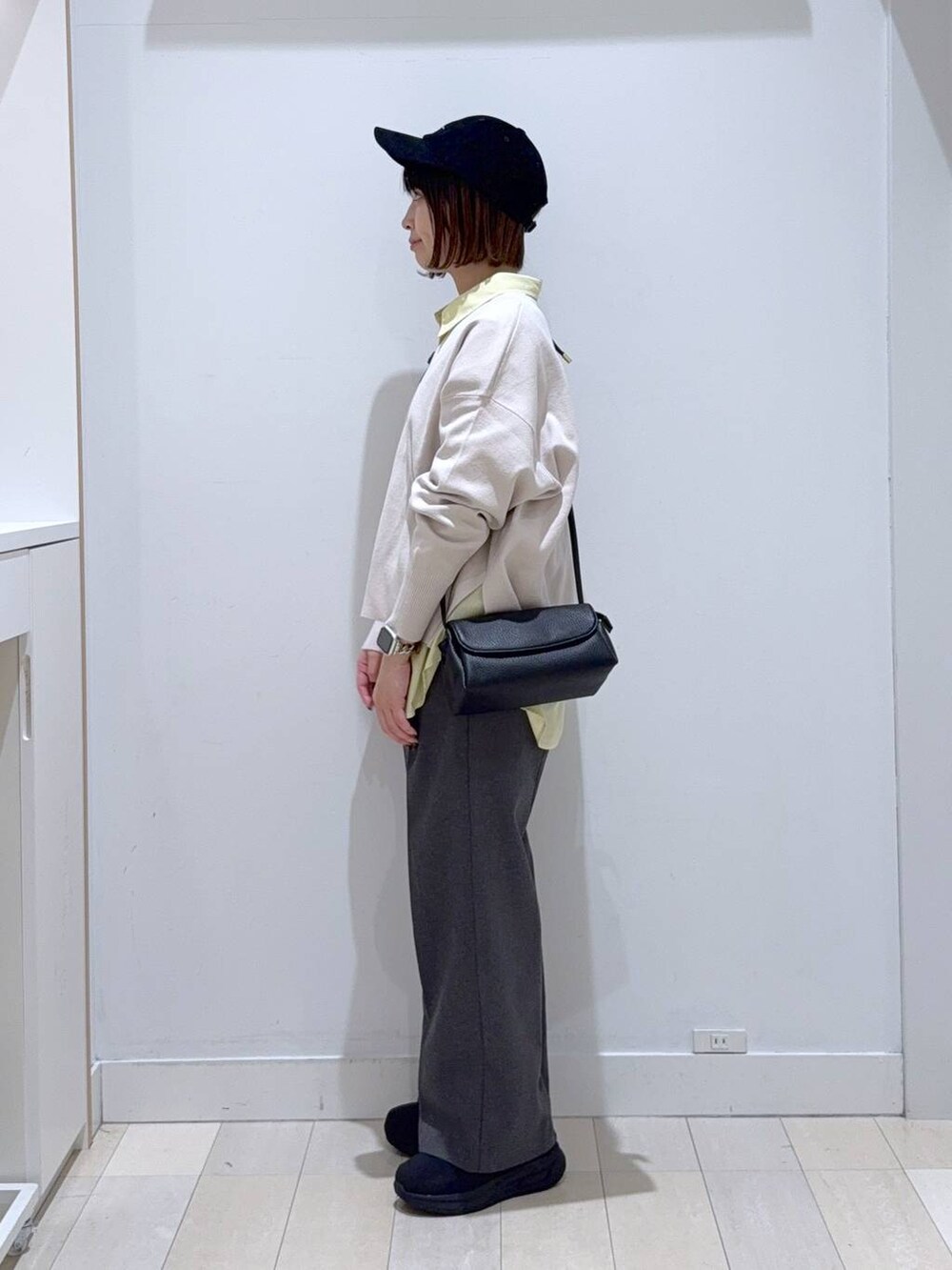 イエロー系のシャツ/ブラウス、ホワイト系のニット/セーター、ブラック系のショルダーバッグを着用したレディースの冬コーディネートの2枚目の写真