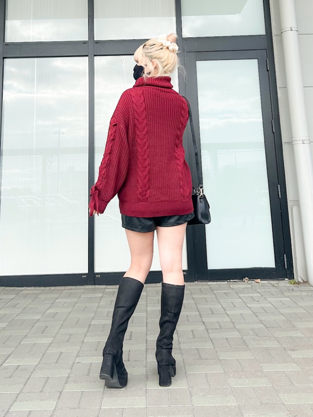 レッド系のチュニック、ブラック系のその他パンツ、ブラック系のハンドバッグを着用したレディースの冬コーディネートの3枚目の写真