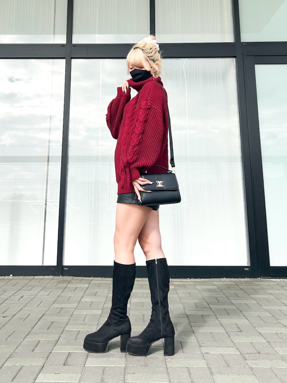 レッド系のチュニック、ブラック系のその他パンツ、ブラック系のハンドバッグを着用したレディースの冬コーディネートの2枚目の写真