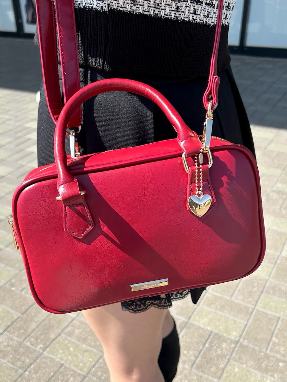 ホワイト系のカーディガン/ボレロ、ブラック系のスカート、レッド系のボストンバッグを着用したレディースの春コーディネートの4枚目の写真