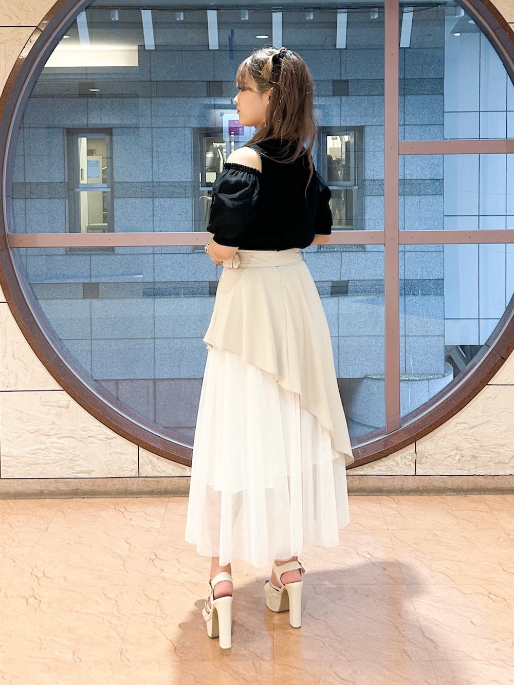 ベージュ系のスカート、ブラック系のニット/セーターを着用したレディースの夏コーディネートの3枚目の写真