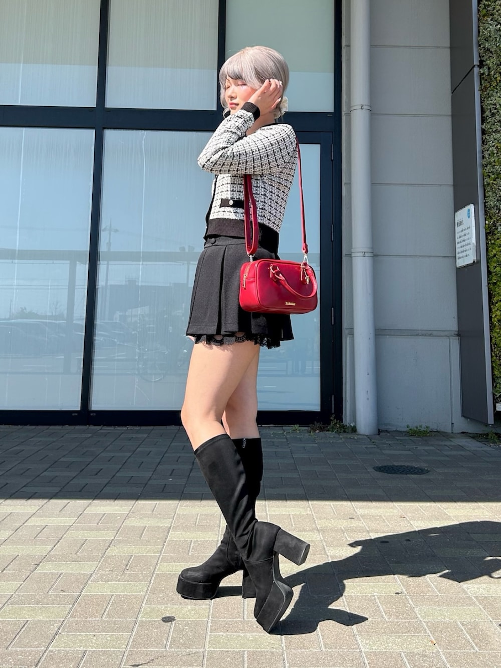 ホワイト系のカーディガン/ボレロ、ブラック系のスカート、レッド系のボストンバッグを着用したレディースの春コーディネートの3枚目の写真