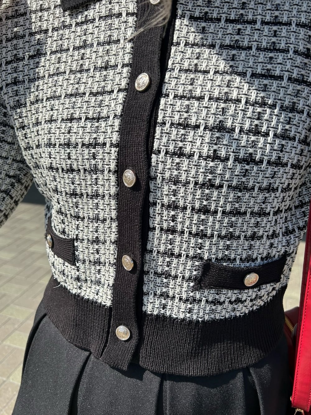 ホワイト系のカーディガン/ボレロ、ブラック系のスカート、レッド系のボストンバッグを着用したレディースの春コーディネートの6枚目の写真