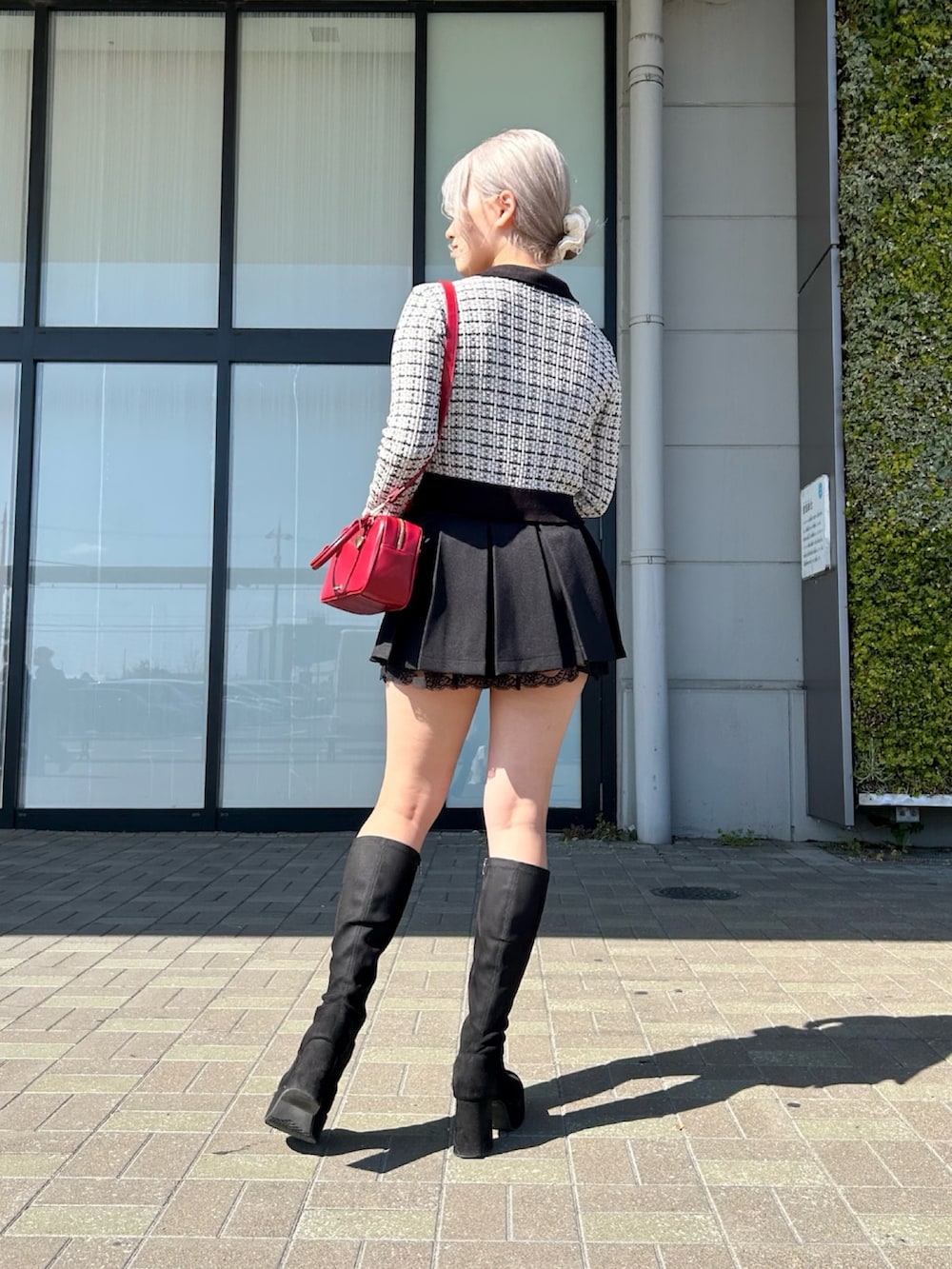 ホワイト系のカーディガン/ボレロ、ブラック系のスカート、レッド系のボストンバッグを着用したレディースの春コーディネートの2枚目の写真