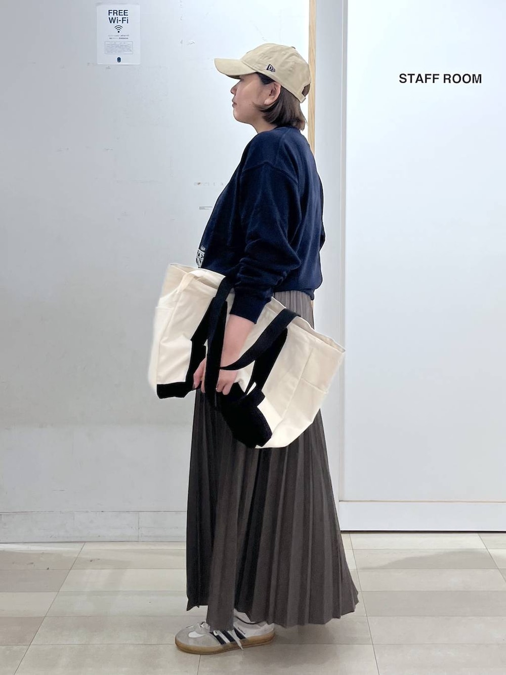 ホワイト系のトートバッグ、ブルー系のスウェット、ベージュ系のスカートを着用したレディースの秋コーディネートの2枚目の写真