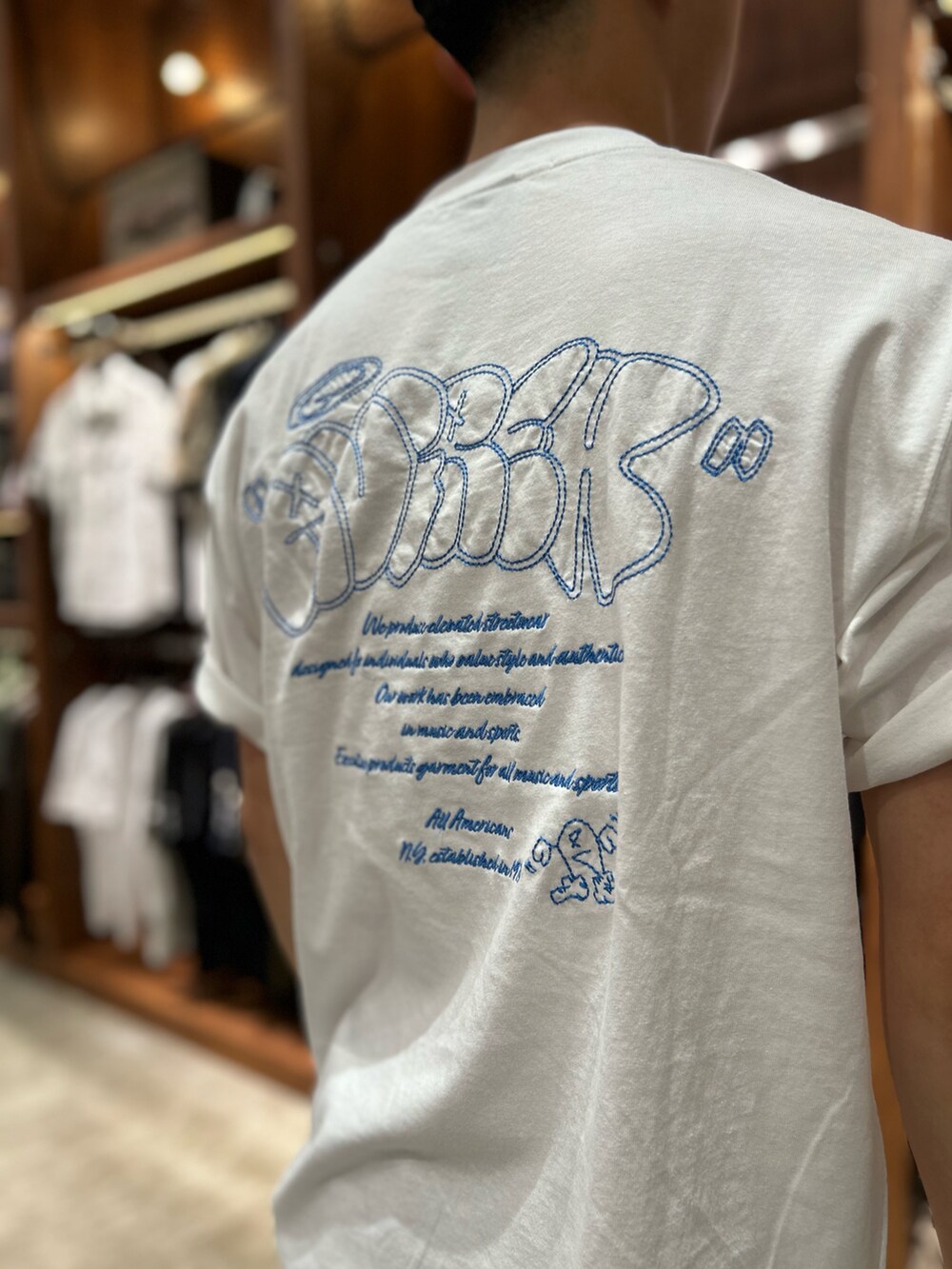 ブルー系のデニムパンツ、ブラック系のトートバッグ、ホワイト系のTシャツ/カットソーを着用したメンズの夏コーディネートの3枚目の写真