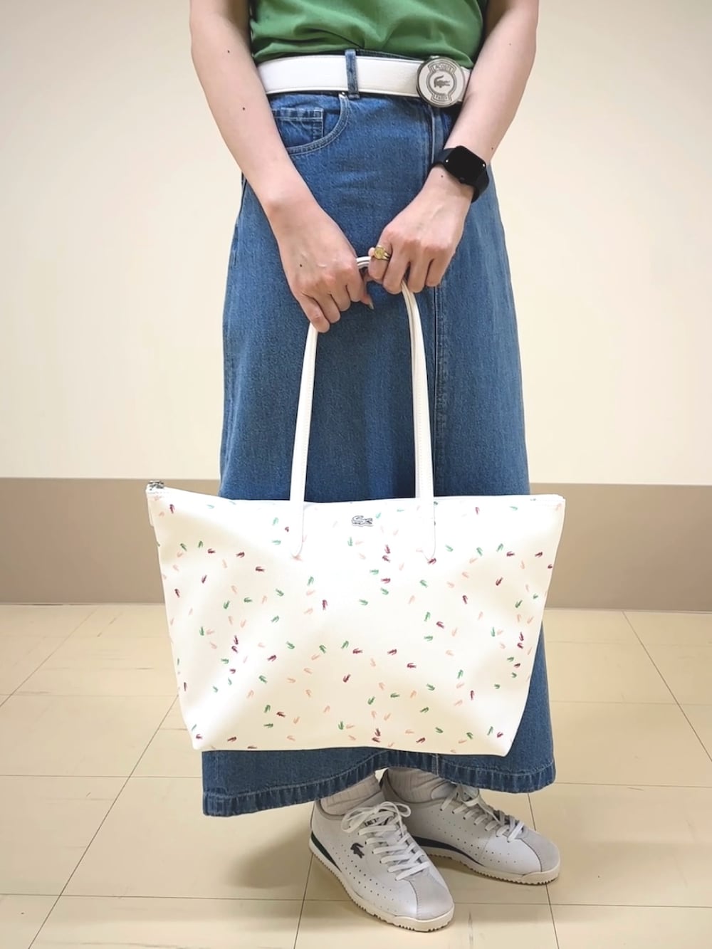 グリーン系のニット/セーター、ブルー系のデニムスカート、ホワイト系のスニーカーを着用したレディースの春コーディネートの3枚目の写真