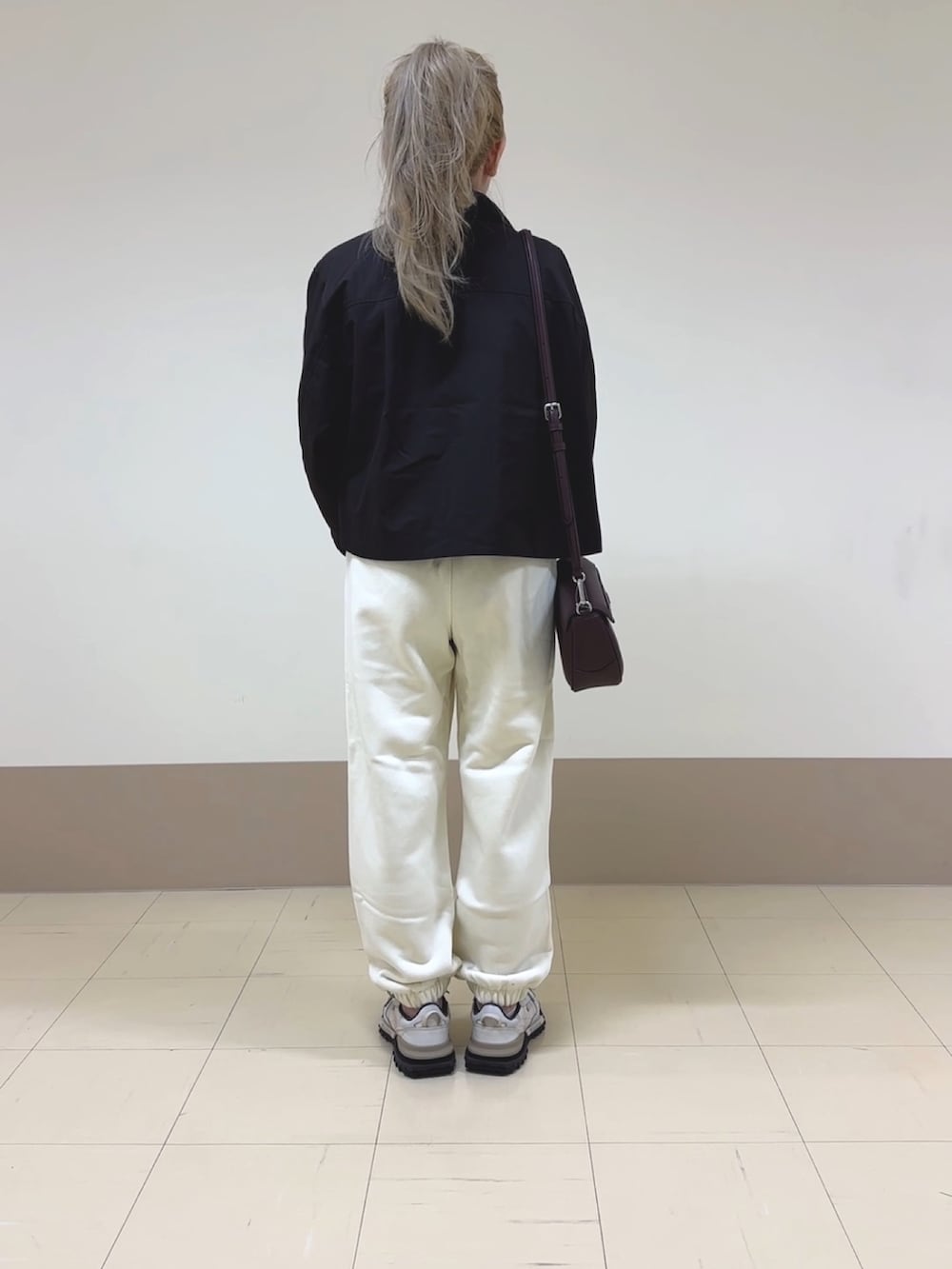 ホワイト系のスウェットパンツ、ベージュ系のスニーカー、ブラウン系のショルダーバッグを着用したレディースの秋コーディネートの3枚目の写真