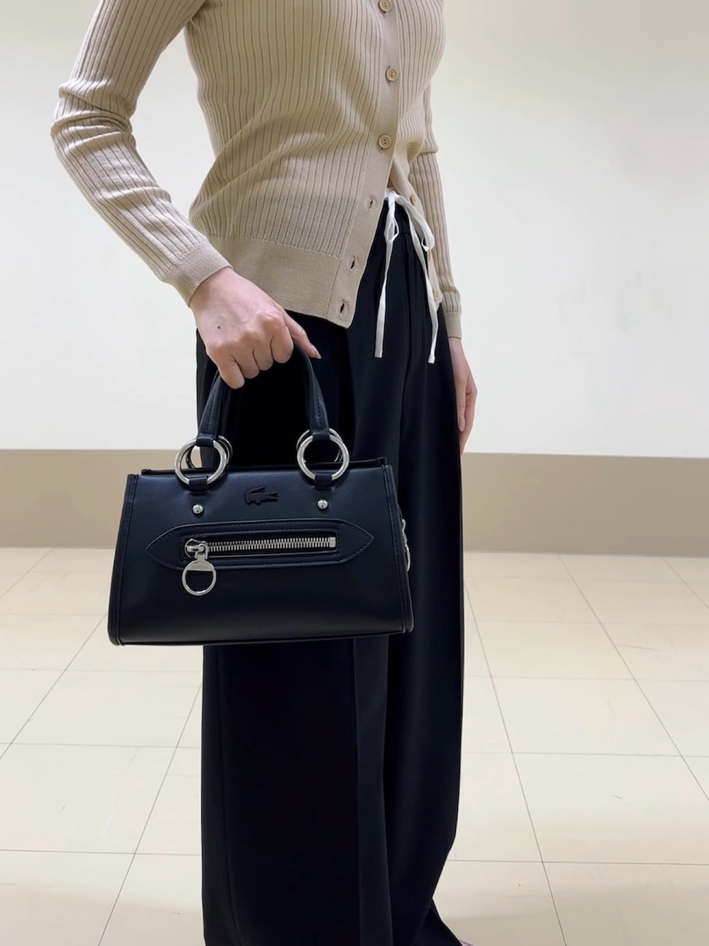 ブラック系のハンドバッグ、ブラック系のパンツ、ピンク系のスニーカーを着用したレディースの冬コーディネートの3枚目の写真