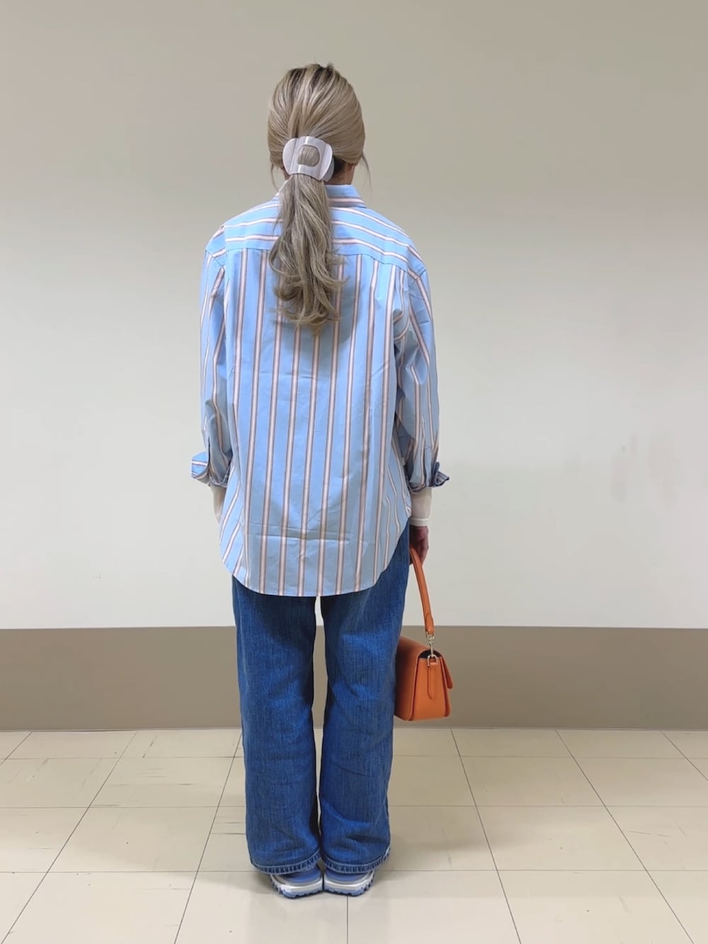 ブルー系のシャツ/ブラウス、ホワイト系のTシャツ/カットソー、オレンジ系のショルダーバッグを着用したレディースの春コーディネートの2枚目の写真