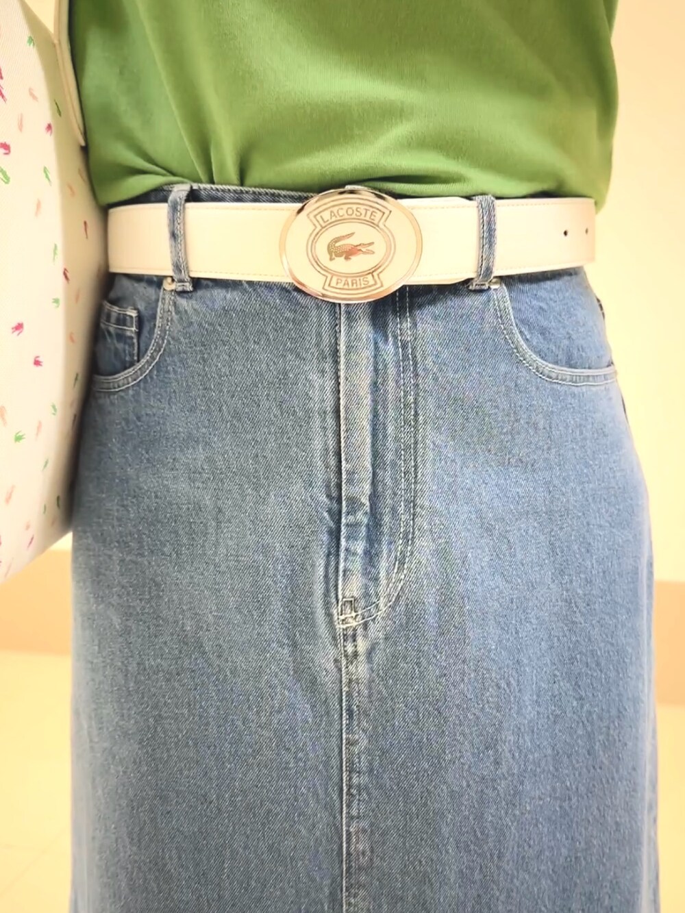 グリーン系のニット/セーター、ブルー系のデニムスカート、ホワイト系のスニーカーを着用したレディースの春コーディネートの5枚目の写真