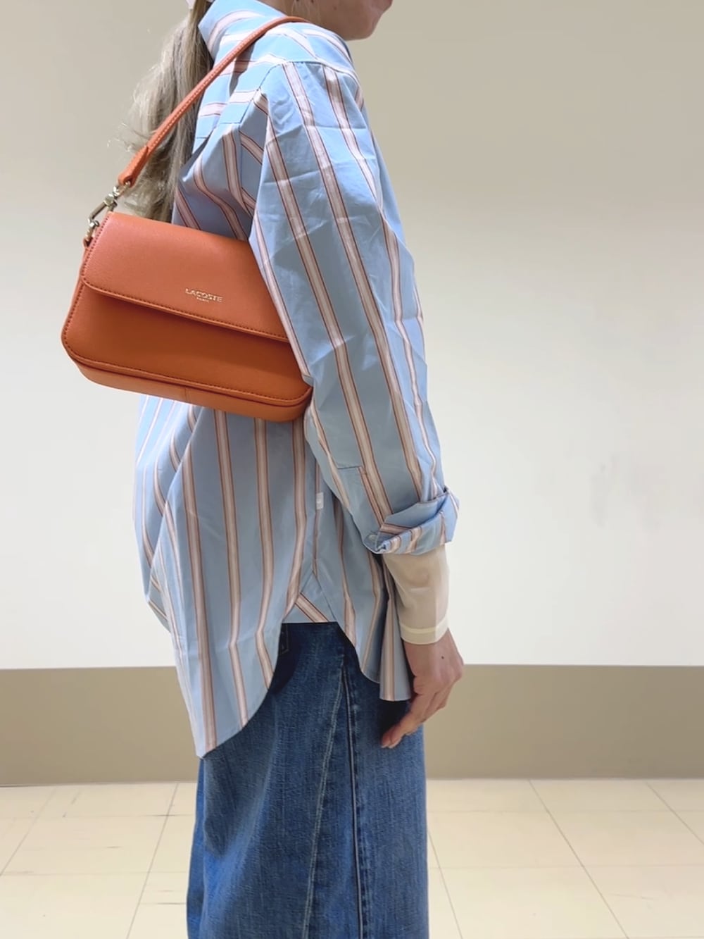 ブルー系のシャツ/ブラウス、ホワイト系のTシャツ/カットソー、オレンジ系のショルダーバッグを着用したレディースの春コーディネートの4枚目の写真