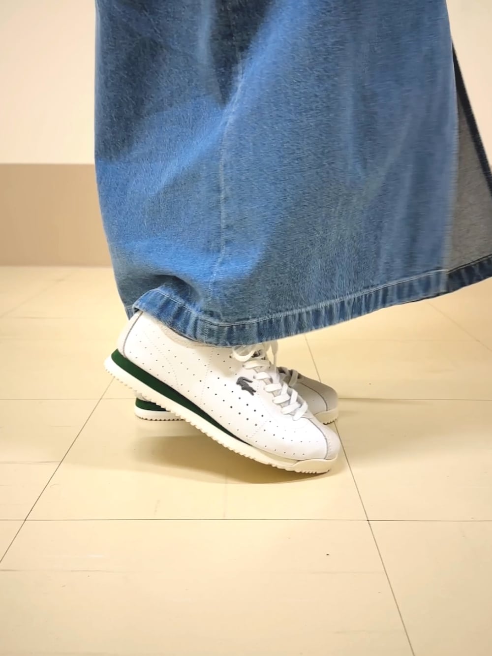 グリーン系のニット/セーター、ブルー系のデニムスカート、ホワイト系のスニーカーを着用したレディースの春コーディネートの4枚目の写真