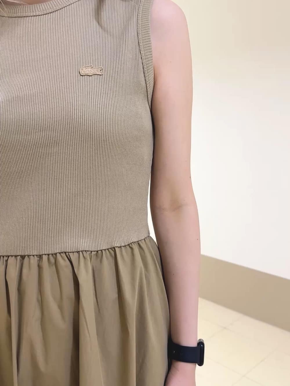ベージュ系のワンピース、ベージュ系のハンドバッグ、ホワイト系のスニーカーを着用したレディースの春コーディネートの5枚目の写真