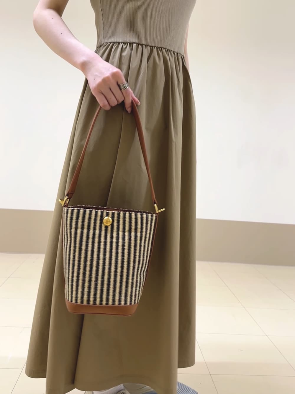 ベージュ系のワンピース、ベージュ系のハンドバッグ、ホワイト系のスニーカーを着用したレディースの春コーディネートの3枚目の写真