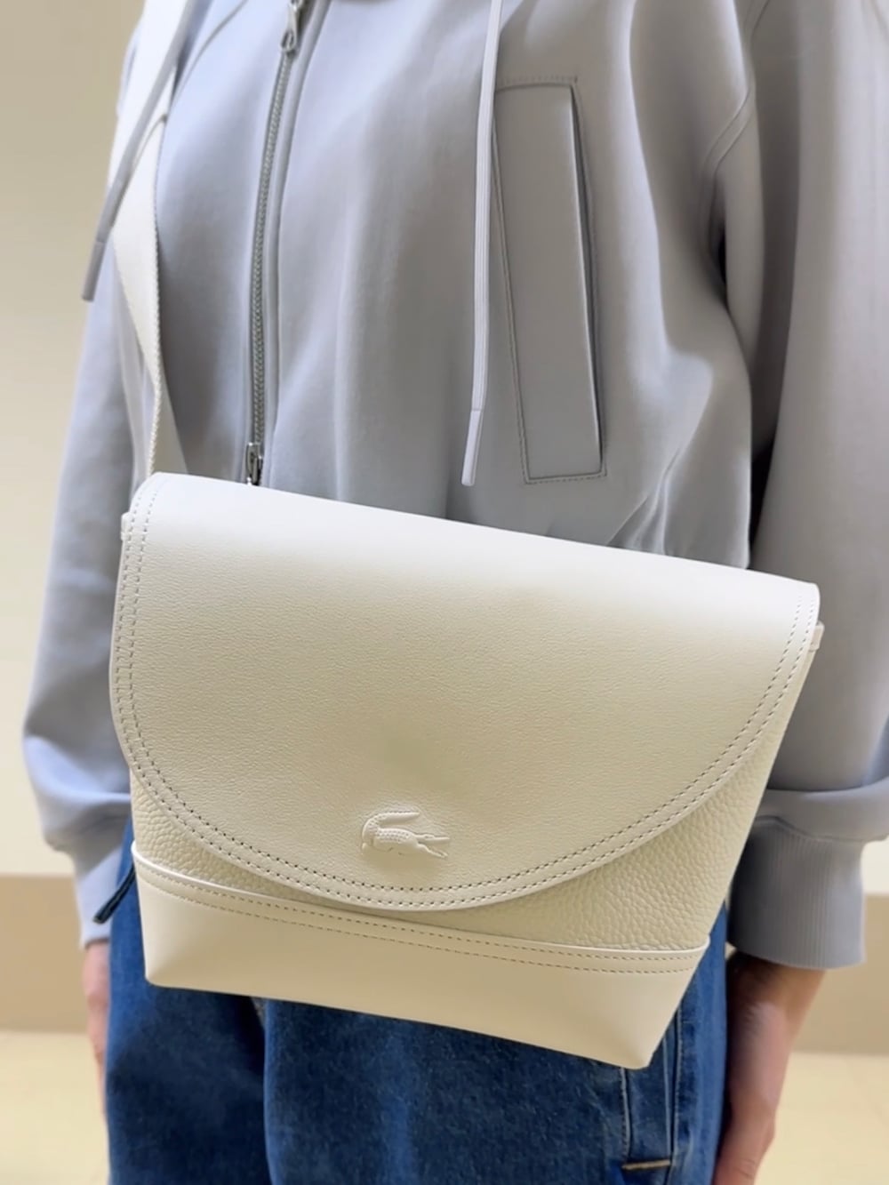 ブルー系のデニムパンツ、ホワイト系のスニーカー、ホワイト系のメッセンジャーバッグを着用したレディースの冬コーディネートの4枚目の写真