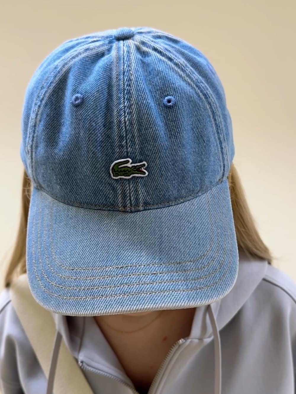 ブルー系のデニムパンツ、ホワイト系のスニーカー、ホワイト系のメッセンジャーバッグを着用したレディースの冬コーディネートの6枚目の写真