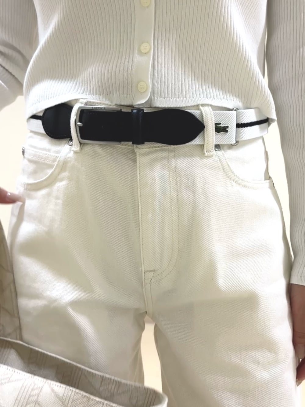 ホワイト系のデニムパンツ、ベージュ系のボストンバッグ、ホワイト系のカーディガン/ボレロを着用したレディースの夏コーディネートの3枚目の写真