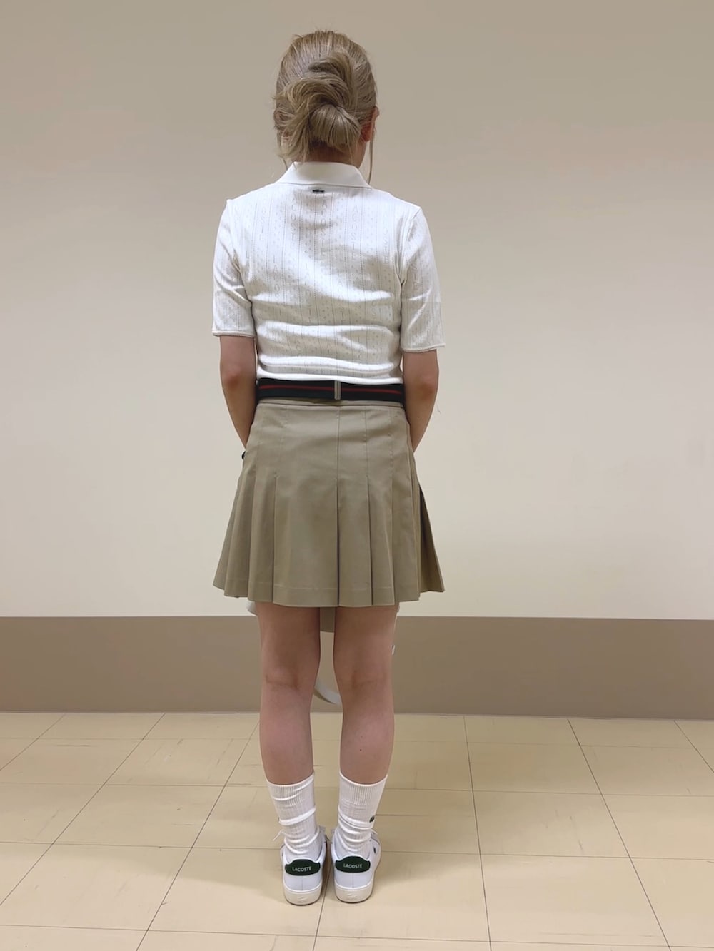 ホワイト系のバッグ、ベージュ系のスカート、ホワイト系のポロシャツを着用したレディースの夏コーディネートの2枚目の写真