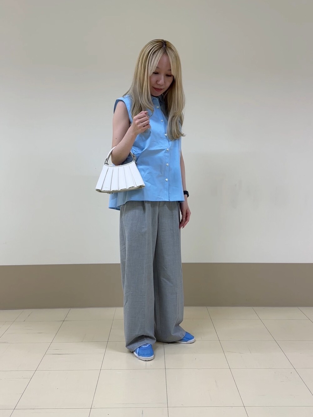 グレー系のスラックス、ホワイト系のショルダーバッグ、ブルー系のスニーカーを着用したレディースの夏コーディネートの2枚目の写真
