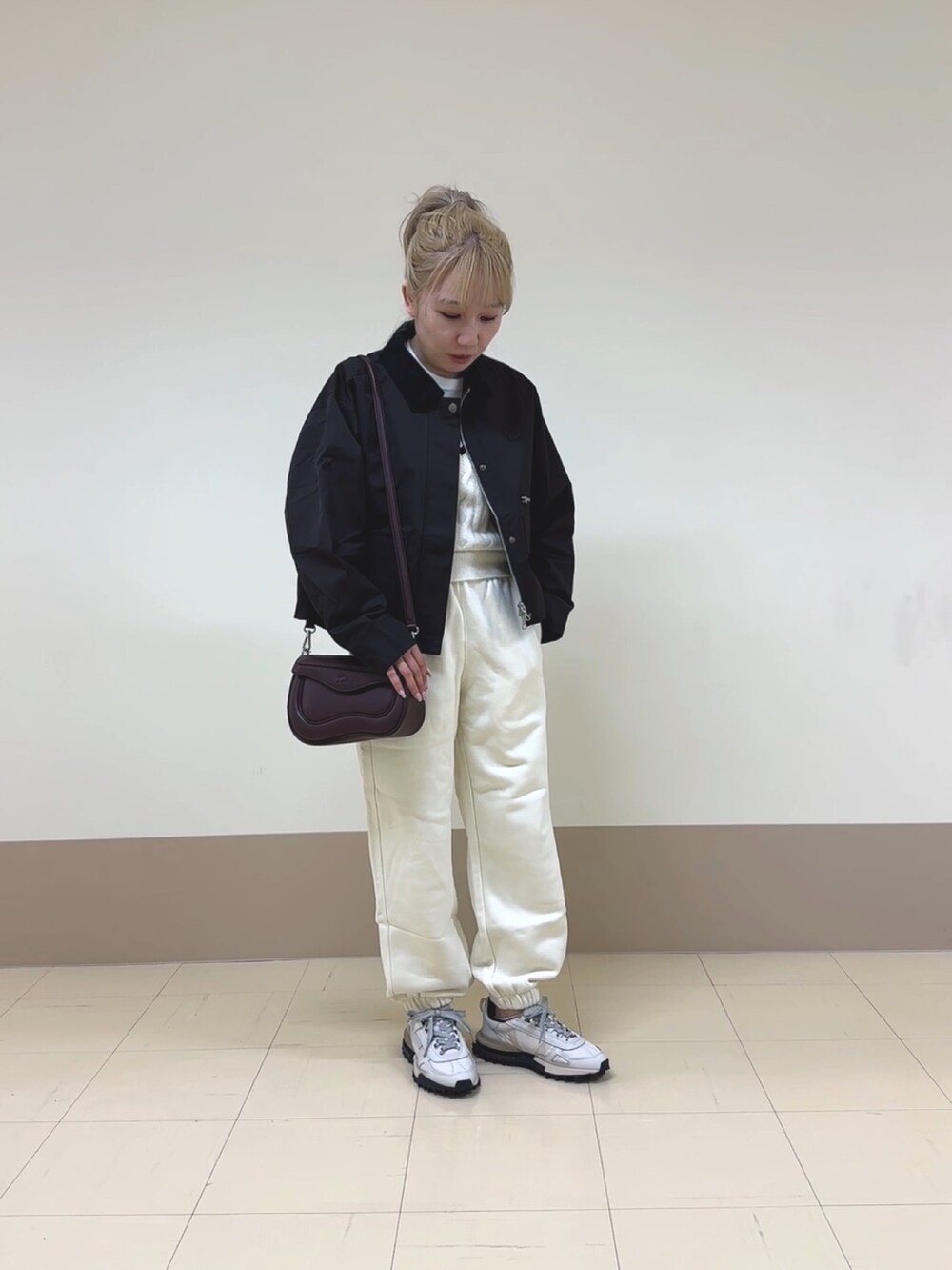 ホワイト系のスウェットパンツ、ベージュ系のスニーカー、ブラウン系のショルダーバッグを着用したレディースの秋コーディネートの2枚目の写真