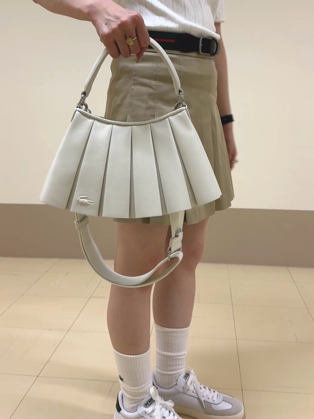 ホワイト系のバッグ、ベージュ系のスカート、ホワイト系のポロシャツを着用したレディースの夏コーディネートの3枚目の写真