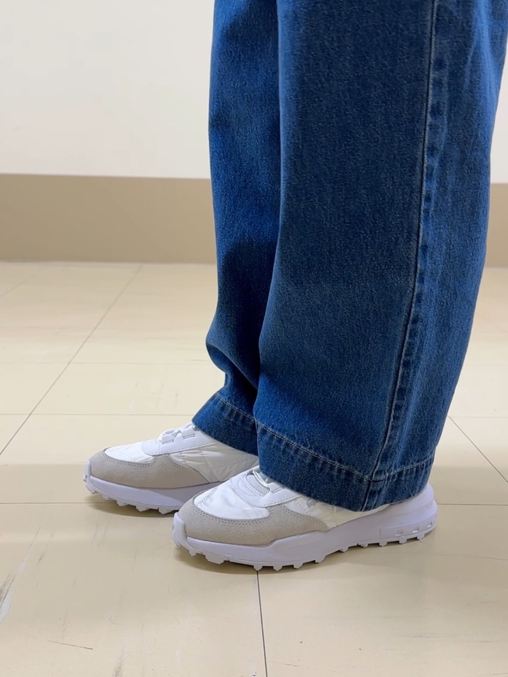 ブルー系のデニムパンツ、ホワイト系のスニーカー、ホワイト系のメッセンジャーバッグを着用したレディースの冬コーディネートの5枚目の写真