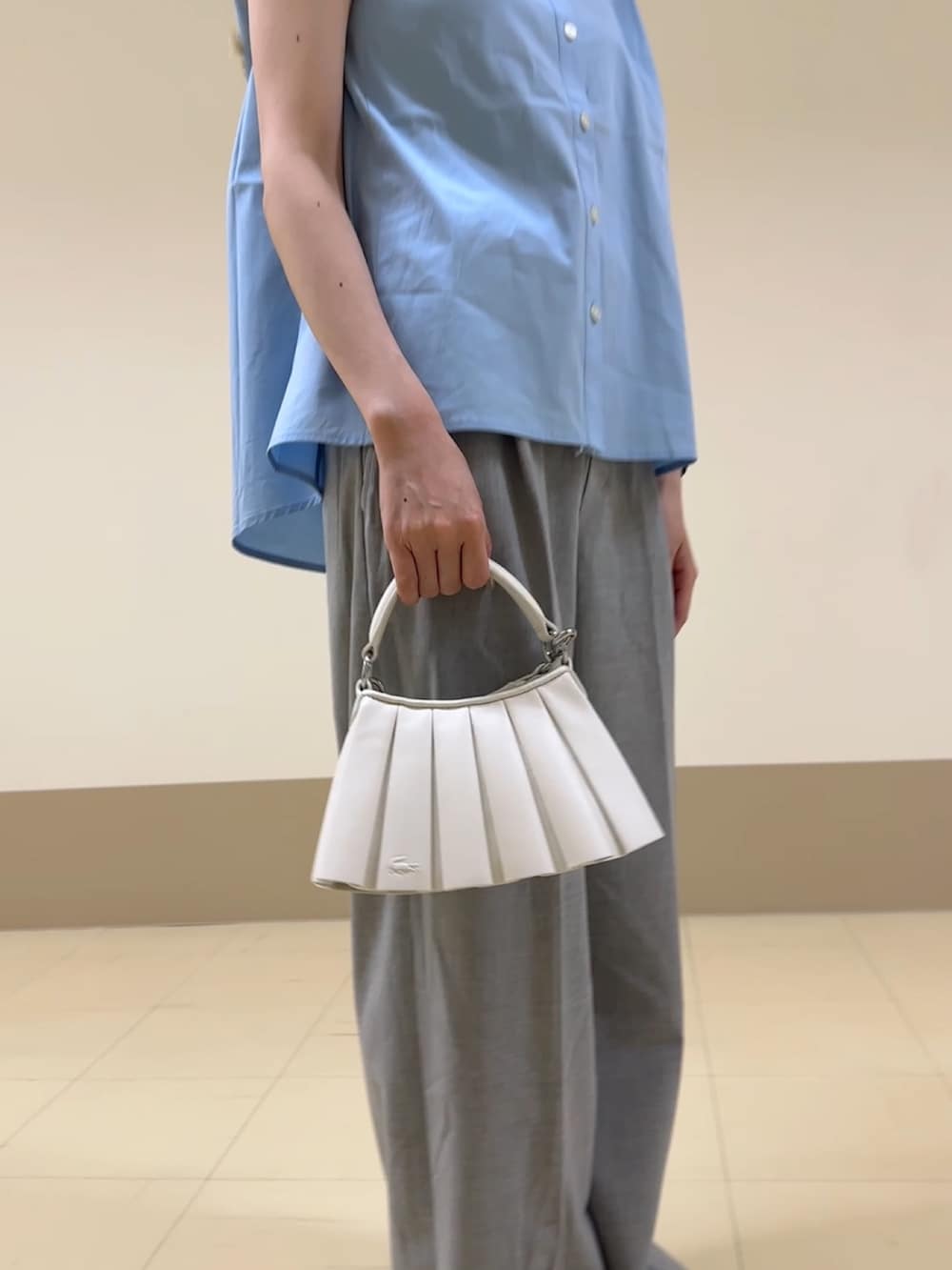 グレー系のスラックス、ホワイト系のショルダーバッグ、ブルー系のスニーカーを着用したレディースの夏コーディネートの4枚目の写真