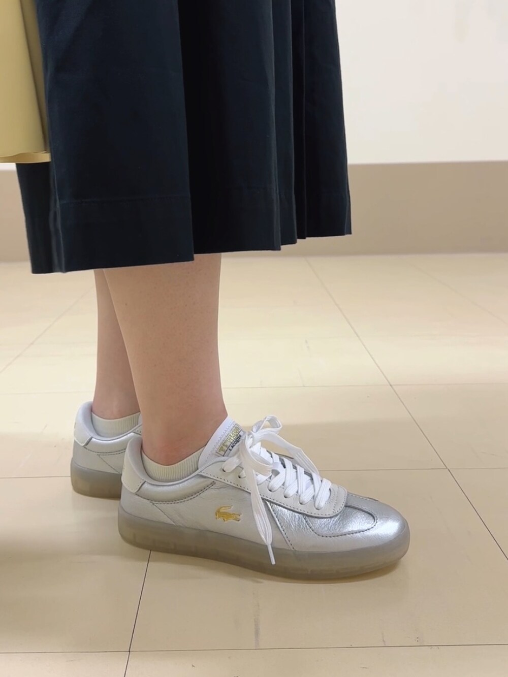 ブラック系のシャツ/ブラウス、イエロー系のハンドバッグ、シルバー系のスニーカーを着用したレディースの秋コーディネートの4枚目の写真