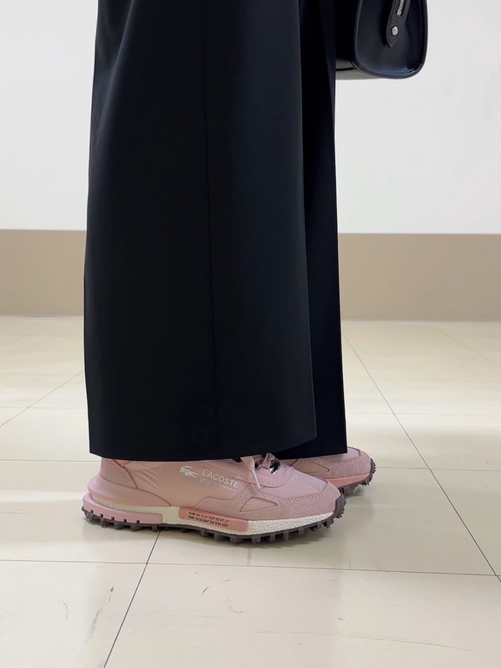 ブラック系のハンドバッグ、ブラック系のパンツ、ピンク系のスニーカーを着用したレディースの冬コーディネートの5枚目の写真