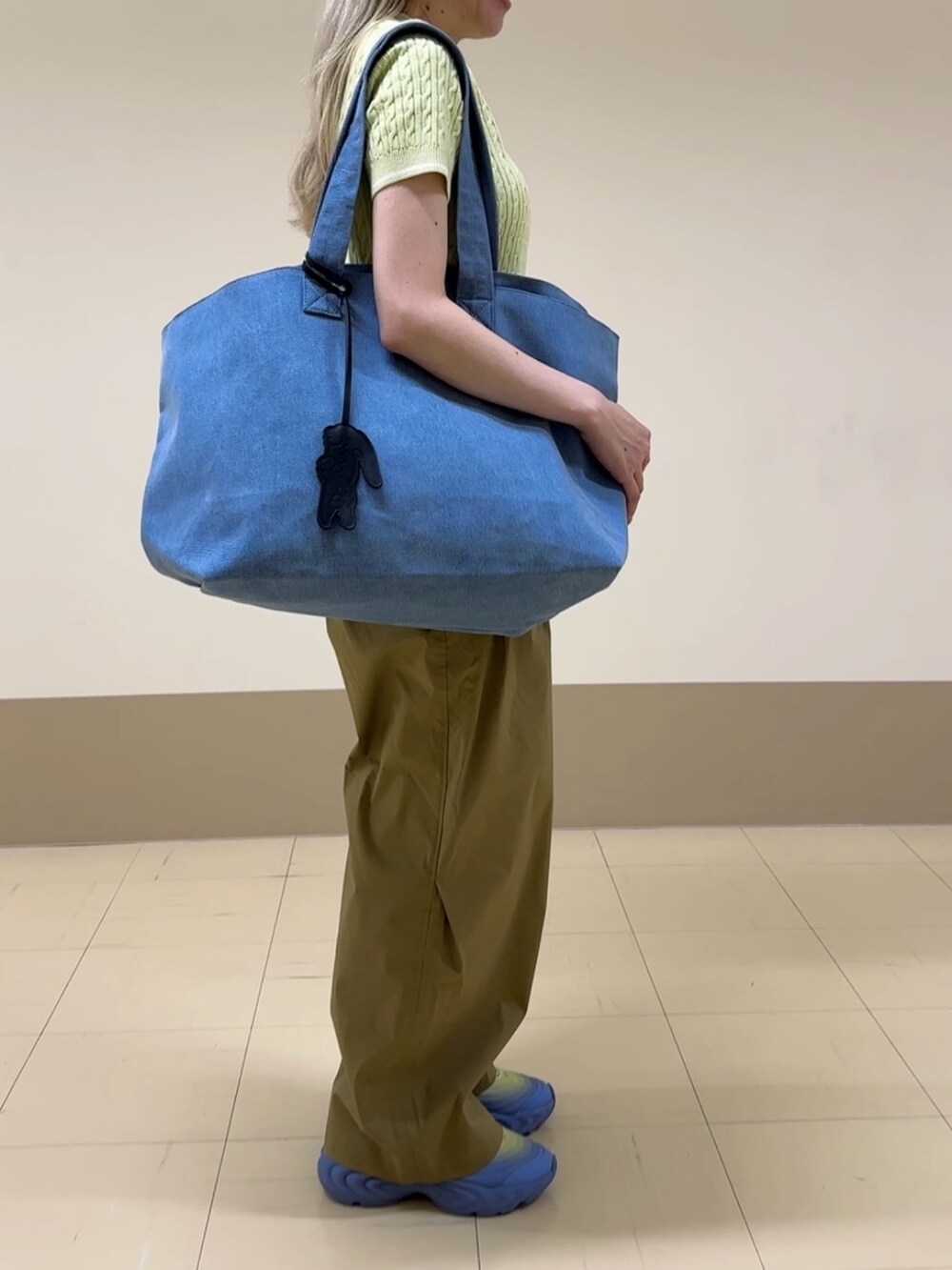 ベージュ系のチノパンツ、グリーン系のスニーカー、ブルー系のトートバッグを着用したレディースの夏コーディネートの3枚目の写真