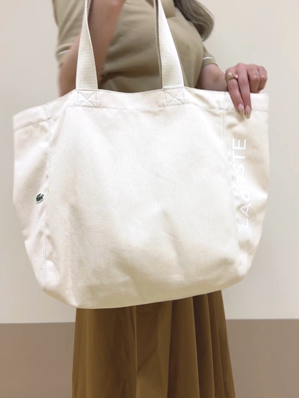 ブラウン系のスカート、ベージュ系のポロシャツ、ホワイト系のスニーカーを着用したレディースの夏コーディネートの3枚目の写真