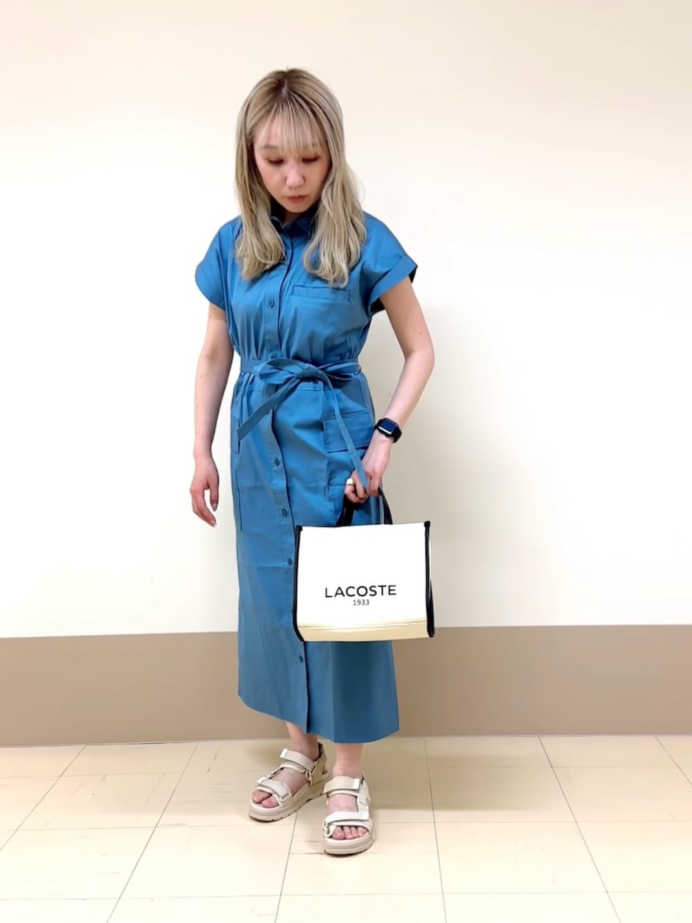 ベージュ系のサンダル、ホワイト系のトートバッグ、ブルー系のシャツワンピースを着用したレディースの春コーディネートの2枚目の写真
