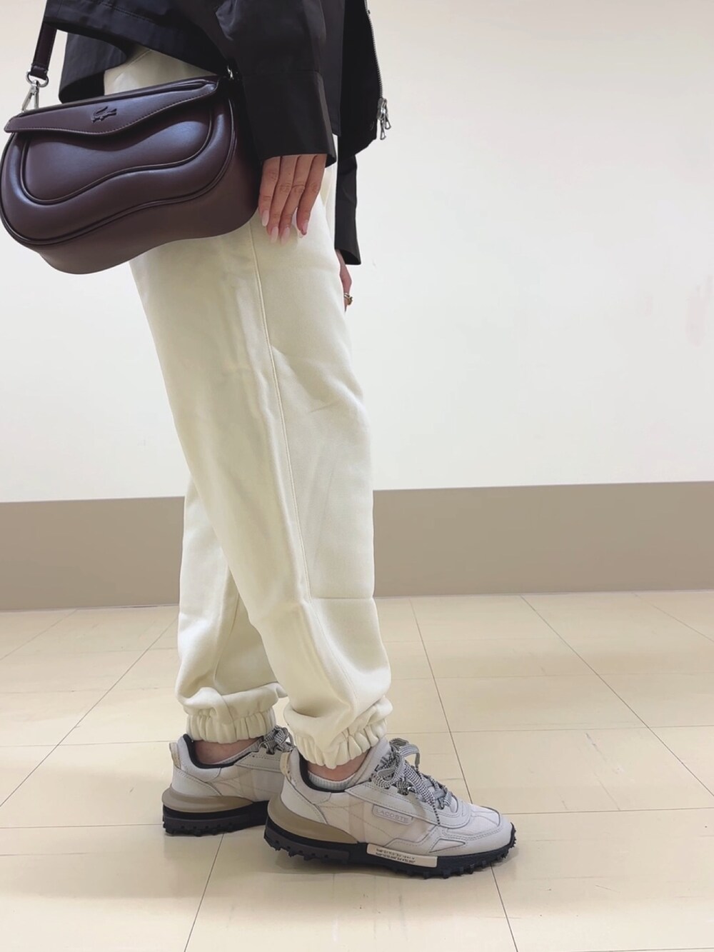 ホワイト系のスウェットパンツ、ベージュ系のスニーカー、ブラウン系のショルダーバッグを着用したレディースの秋コーディネートの9枚目の写真
