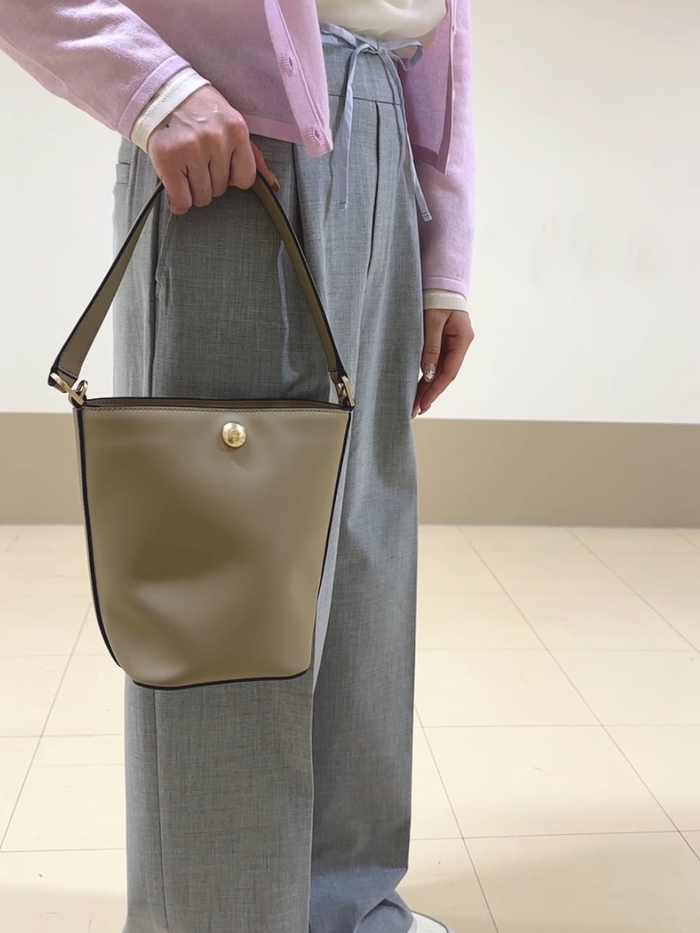 ピンク系のカーディガン/ボレロ、ホワイト系のTシャツ/カットソー、グレー系のスラックスを着用したレディースの春コーディネートの3枚目の写真