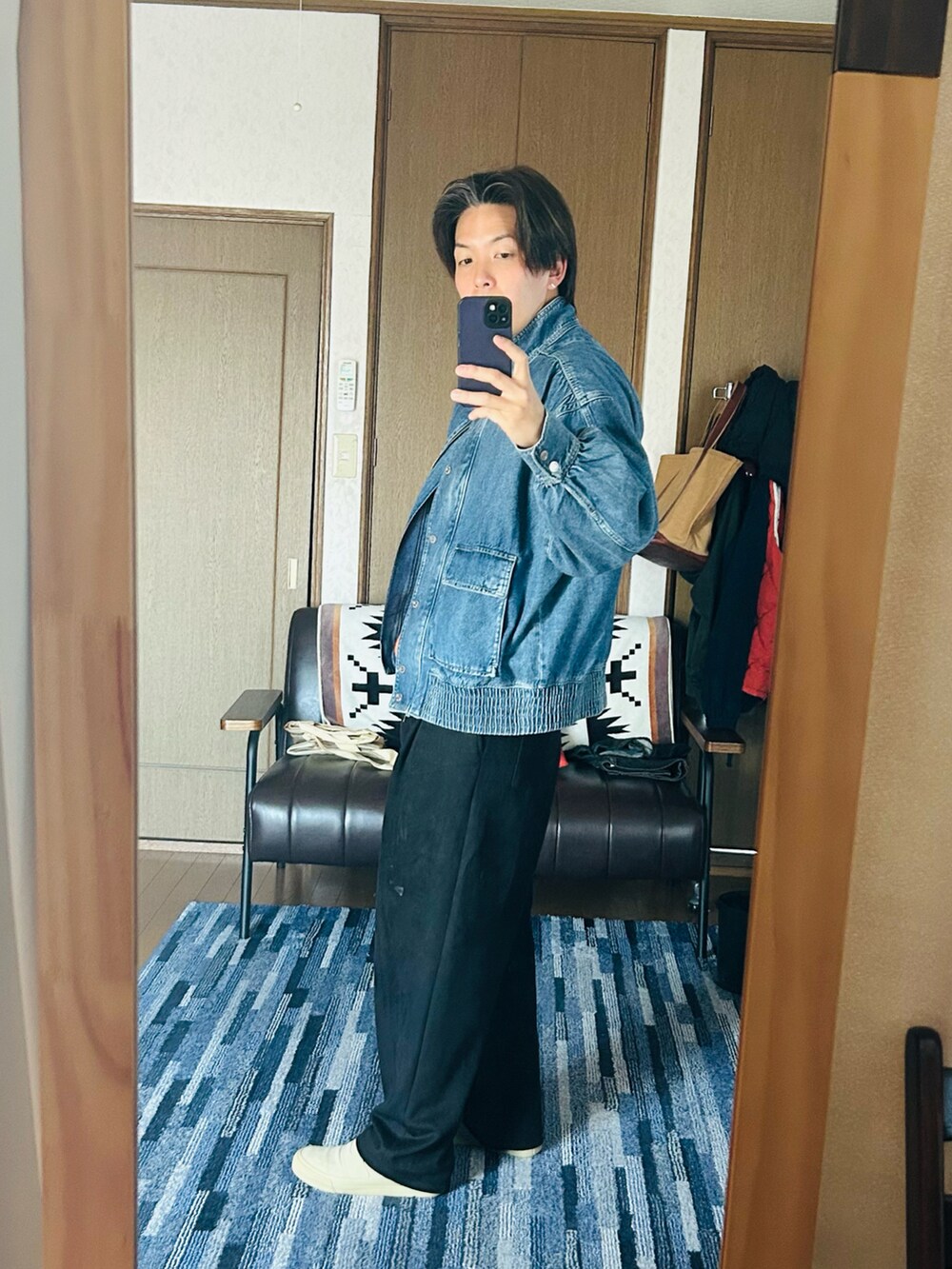 ブルー系のデニムジャケット、オレンジ系のニット/セーター、ブラック系のスウェットパンツを着用したメンズの春コーディネートの4枚目の写真