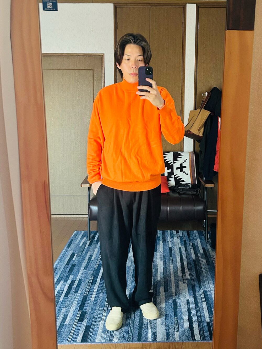 ブルー系のデニムジャケット、オレンジ系のニット/セーター、ブラック系のスウェットパンツを着用したメンズの春コーディネートの3枚目の写真