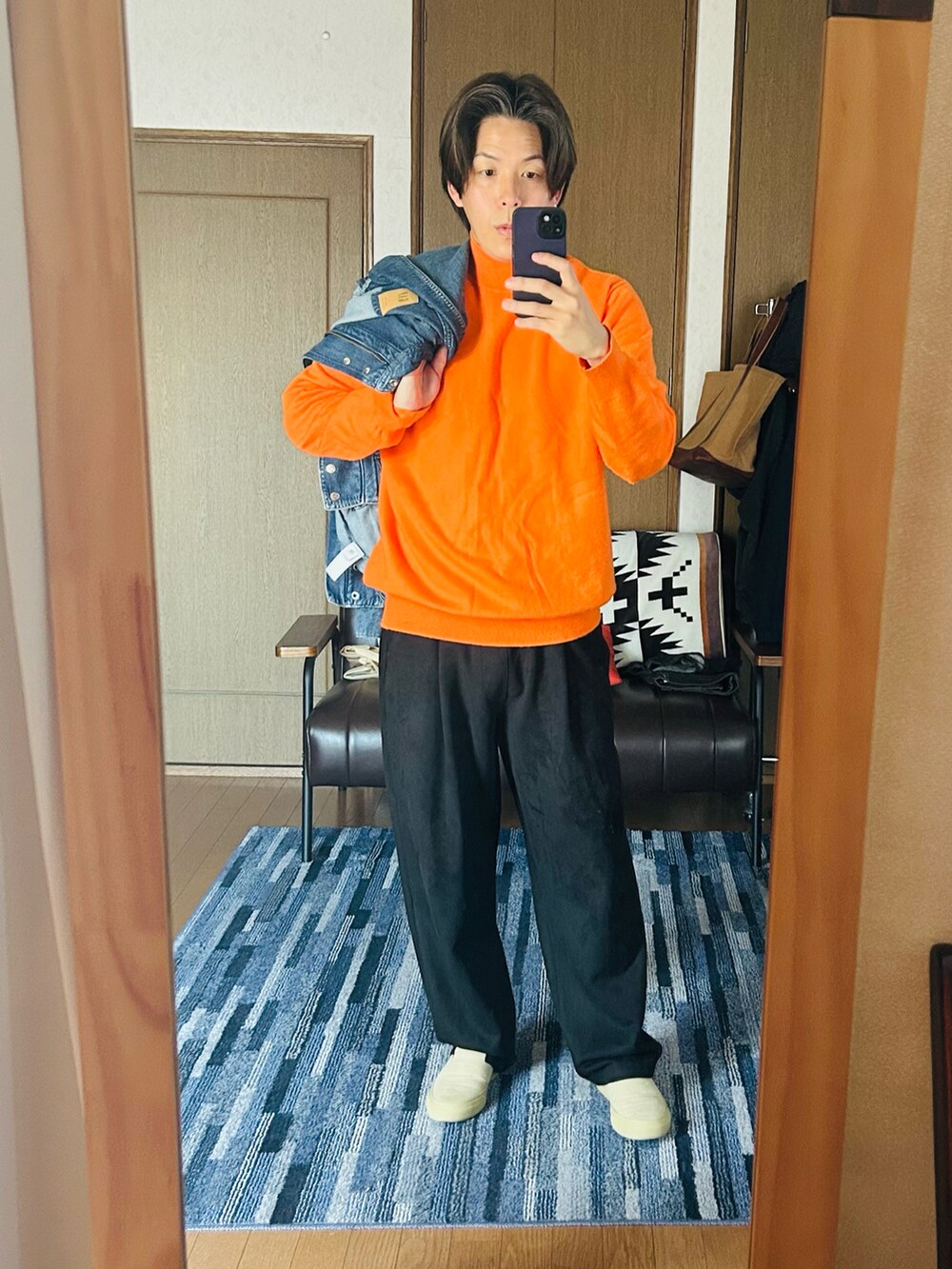 ブルー系のデニムジャケット、オレンジ系のニット/セーター、ブラック系のスウェットパンツを着用したメンズの春コーディネートの2枚目の写真