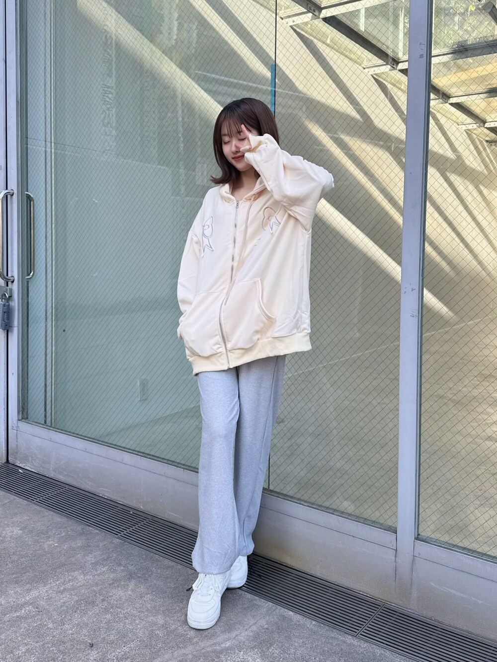 ホワイト系のパーカー、グレー系のスウェットパンツを着用したレディースの冬コーディネートの2枚目の写真