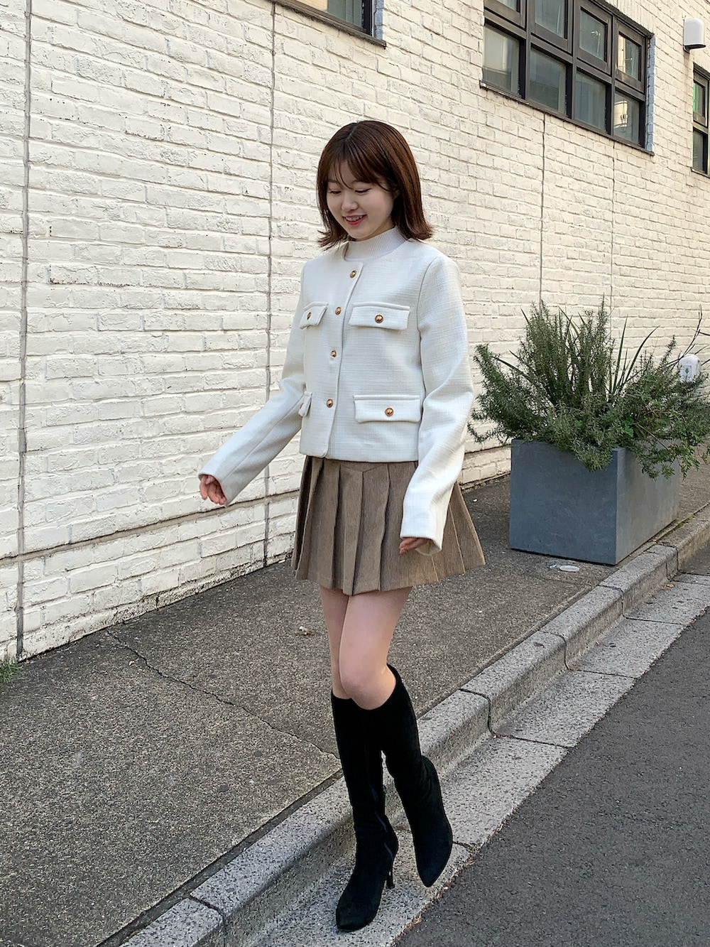 ベージュ系のスカート、ホワイト系のジャケット/アウターを着用したレディースの冬コーディネートの2枚目の写真