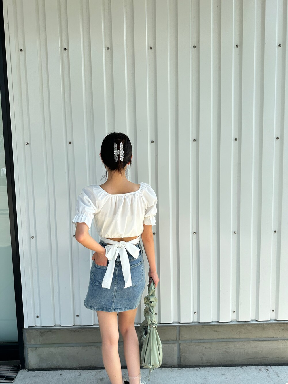 ブルー系のデニムスカート、ホワイト系のスニーカーを着用したレディースの夏コーディネートの2枚目の写真