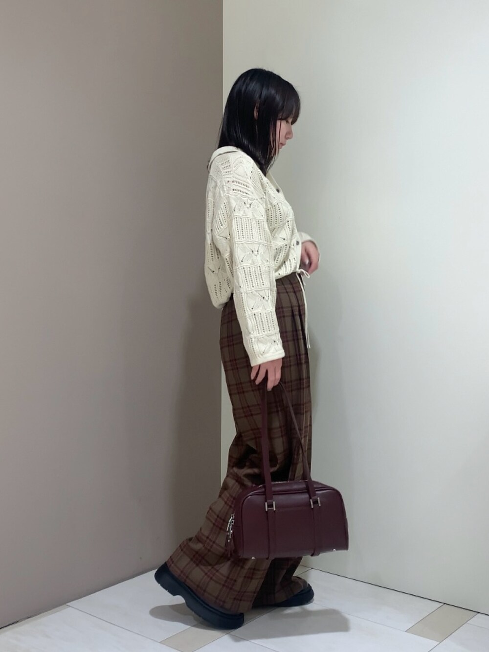 レッド系のボストンバッグ、ホワイト系のカーディガン/ボレロ、レッド系のその他パンツを着用したレディースの秋コーディネートの2枚目の写真