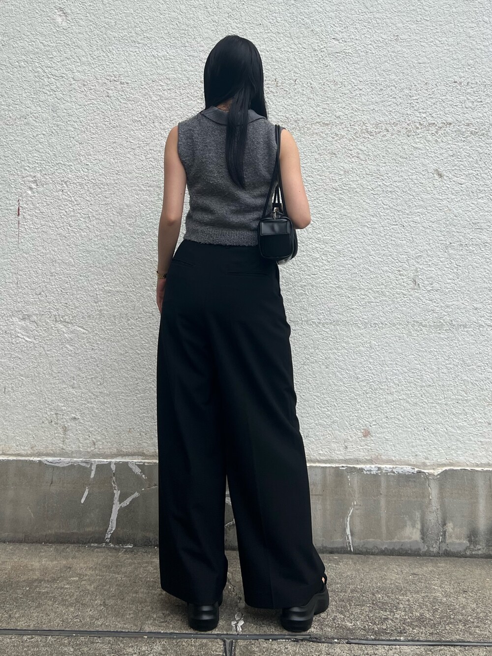 グレー系のニット/セーター、ブラック系のその他パンツ、ブラック系のハンドバッグを着用したレディースの夏コーディネートの3枚目の写真